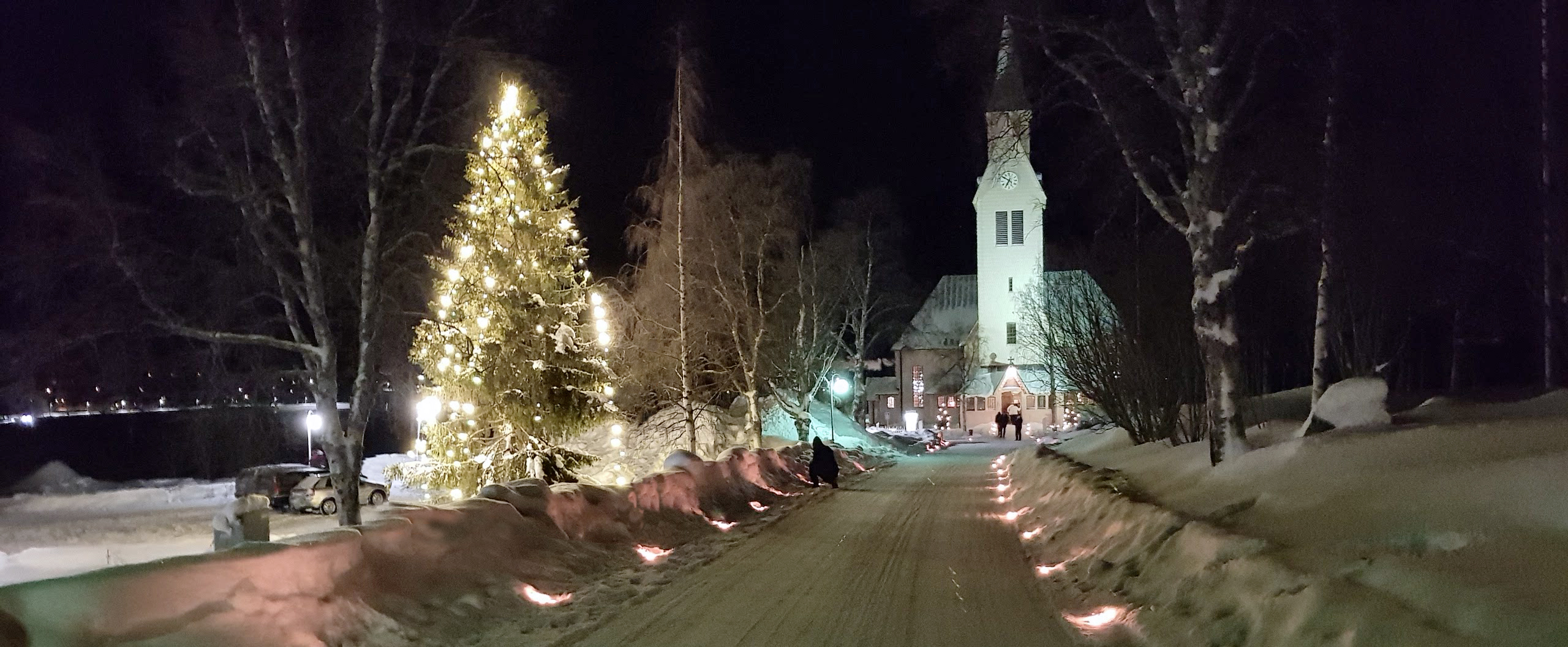 Bild på den upplysta kyrkan och den stora julgranen på Arjeplogs torg.