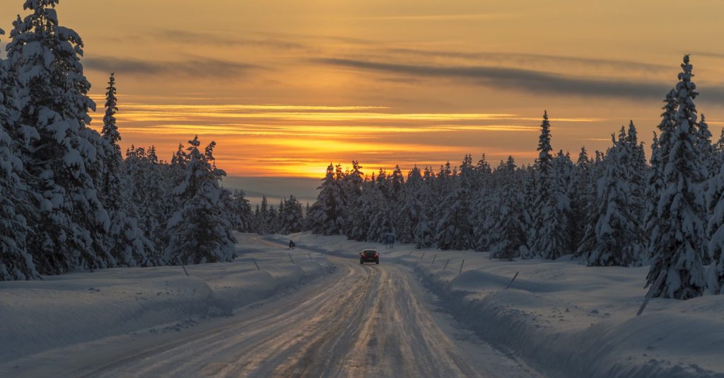 En bil kör iväg i skymningen på Silvervägen en vintereftermiddag.