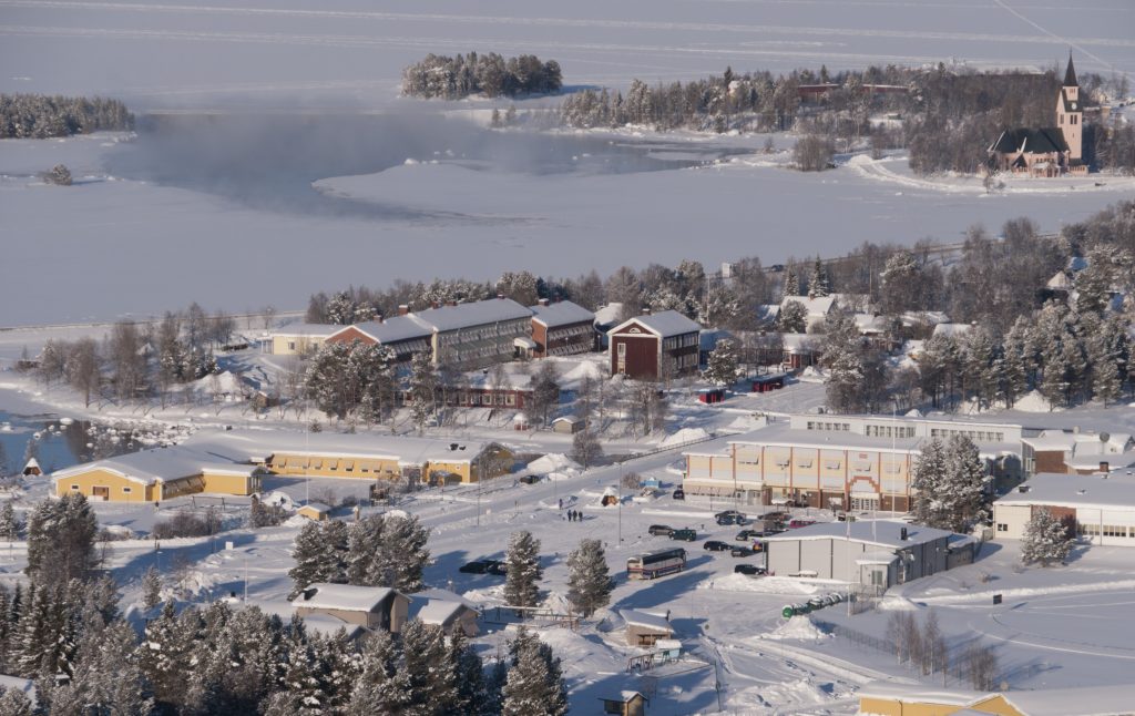 Flygbild över skolorna i Arjeplog. Bilden är tagen på vintern med snö marken och is på sjöarna