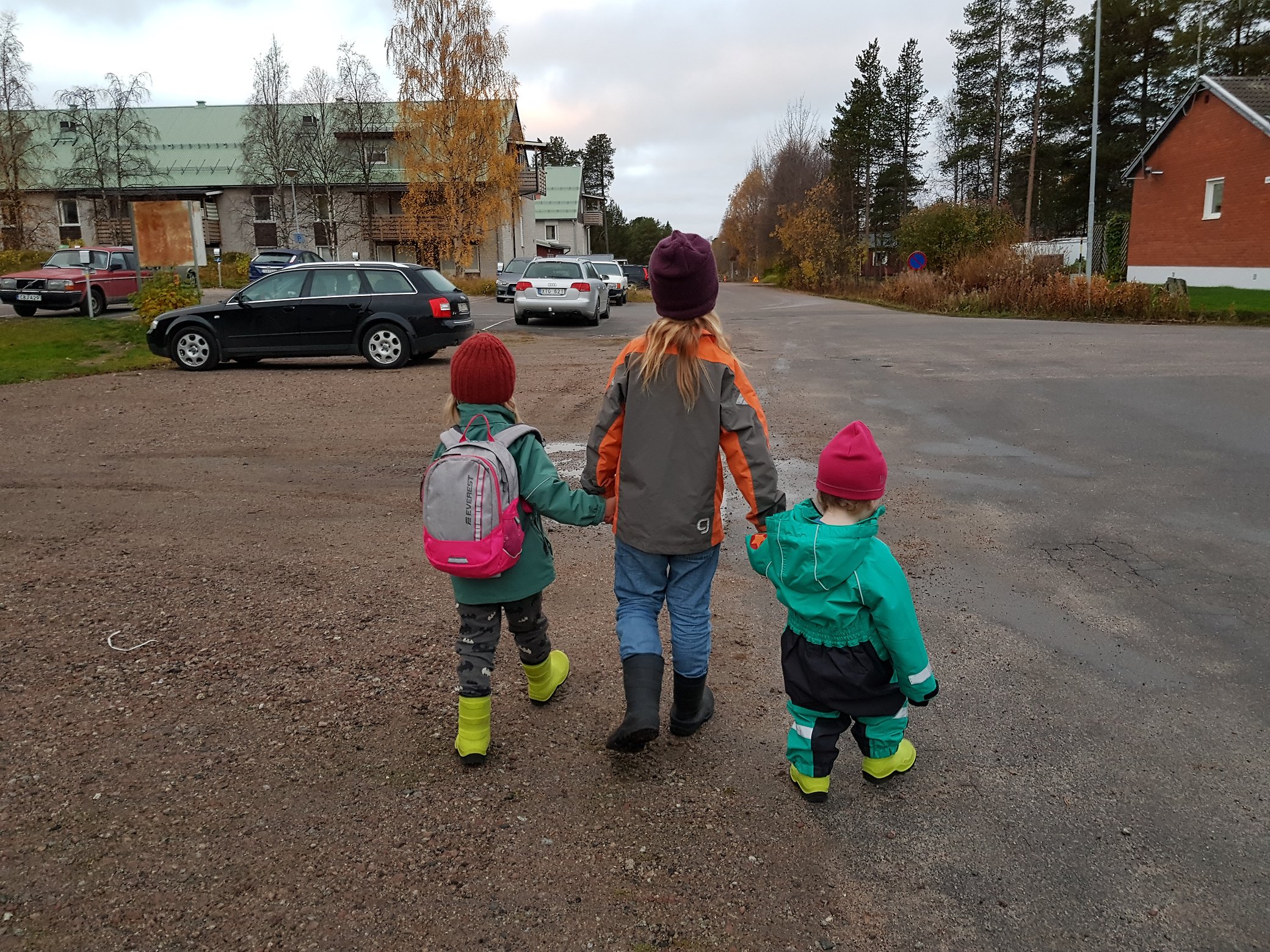 Tre barn håller varandra i handen och promenerar