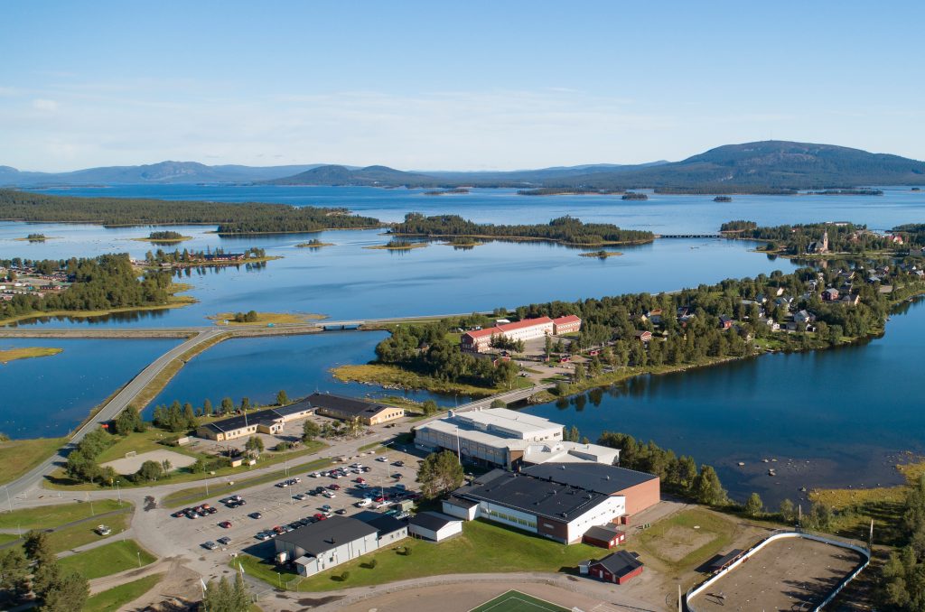 En flygvy över Arjeplogs campus, med Hornavan och Galtis i bakgrunden, en sommardag.