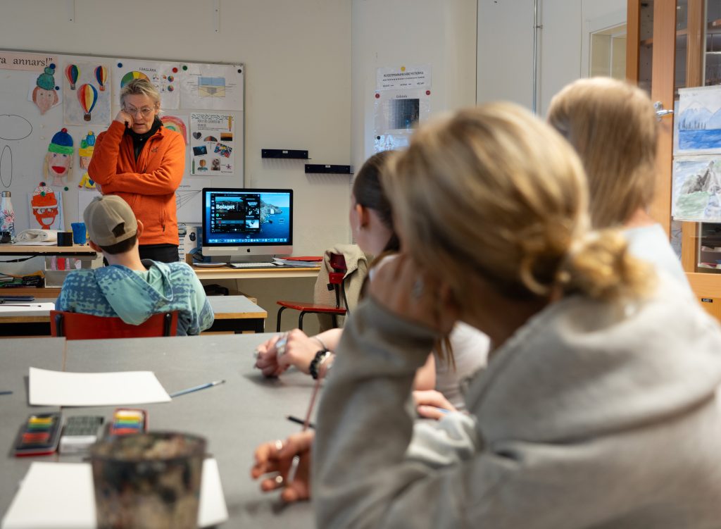 Lars Lerin står framför eleverna i klassrummet och pratar, med armarna i kors.