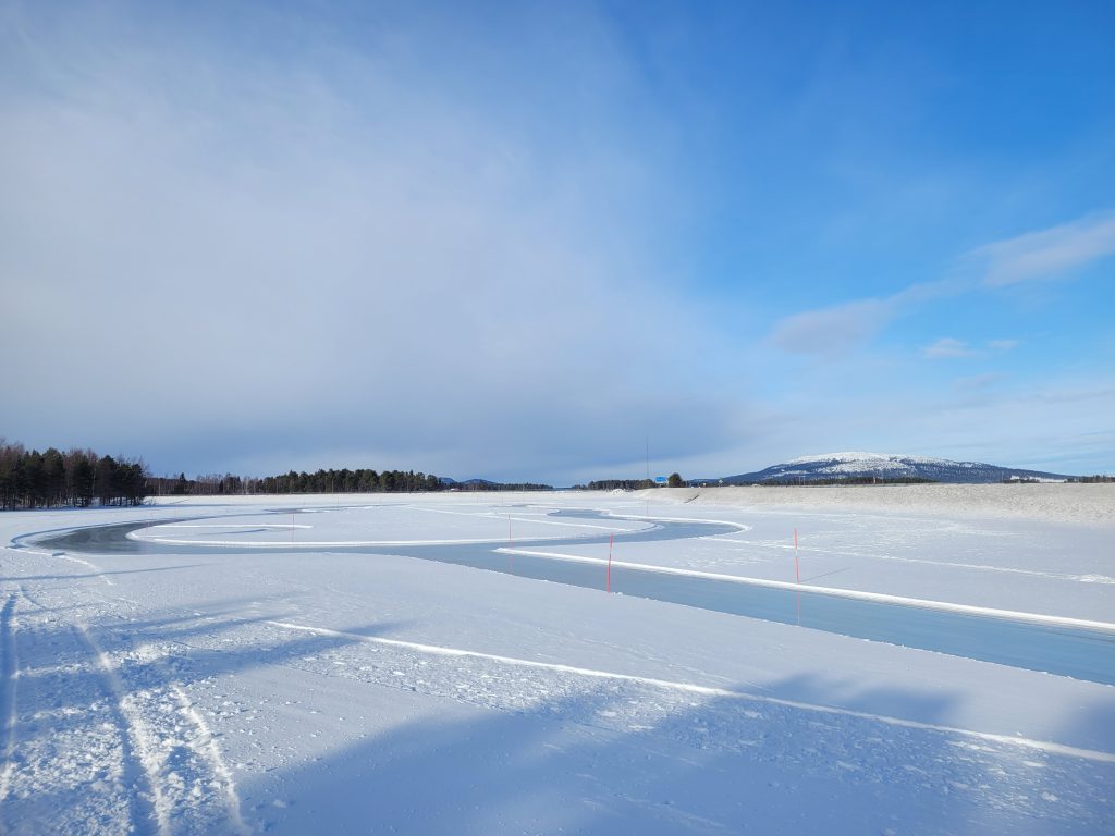 En upplogad skridskobana på en liten sjö en solig vinterdag.