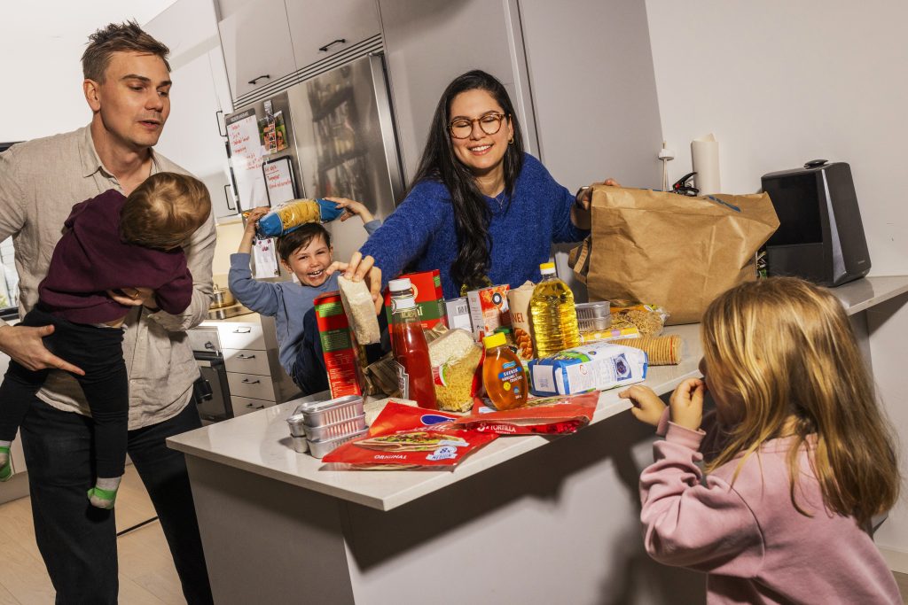En familj som preppar en beredskapslåda i sitt kök, med sina barn till hjälp. Foto: MSB