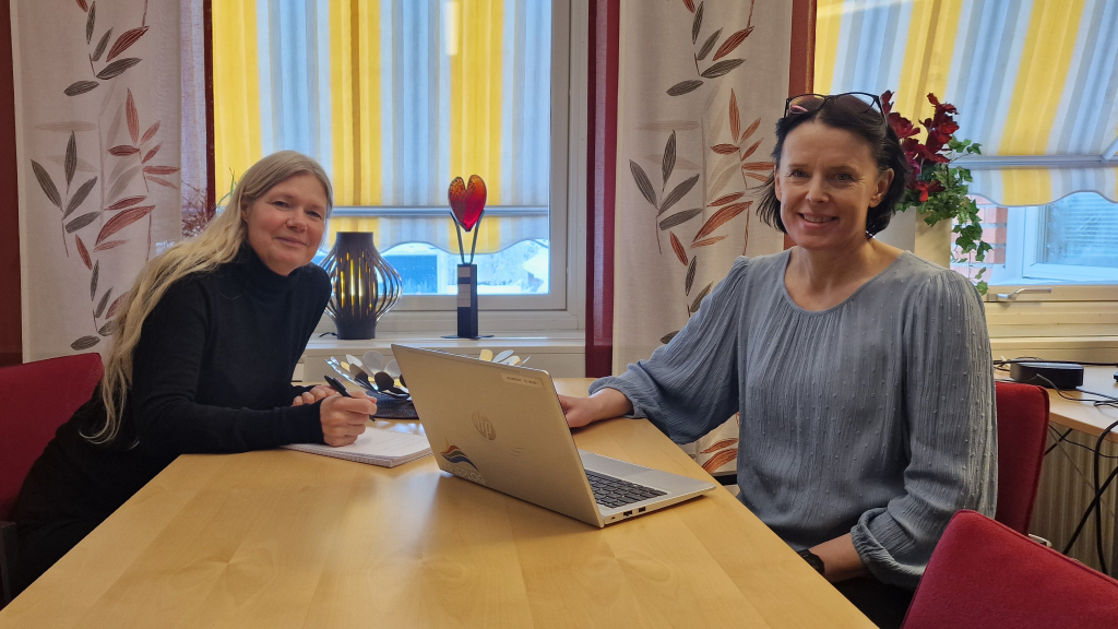Lotta och Anna sitter mitt emot varandra vid ett bord.