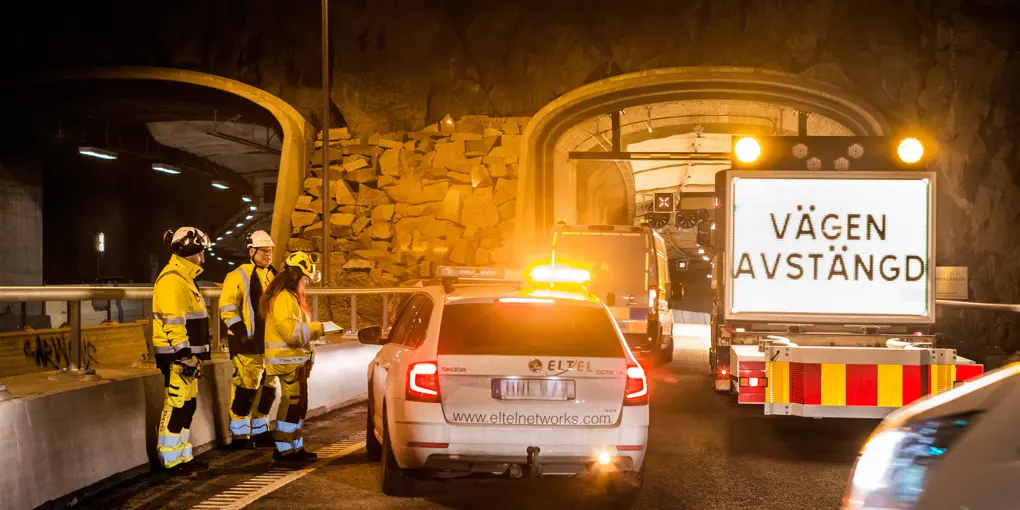 Personal och bilar kvällstid framför en avstängd tunnel.