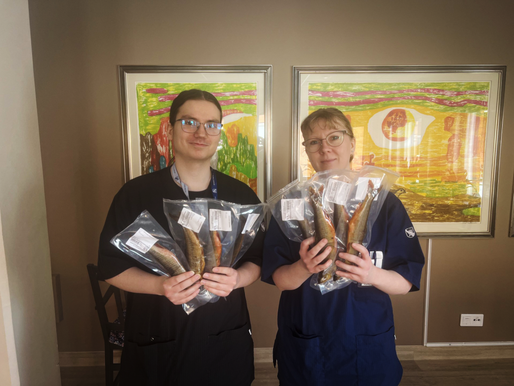 Två personer håller i över två kilo fryst röding.