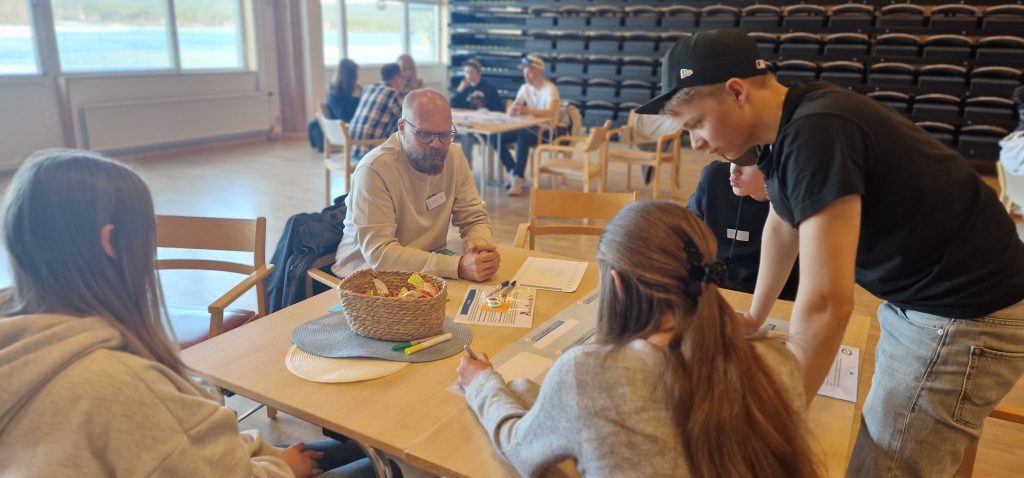Emil Sundström, samhällsbyggnadschef, sitter i samtal med ungdomar vid ett bord i Medborgarhuset.