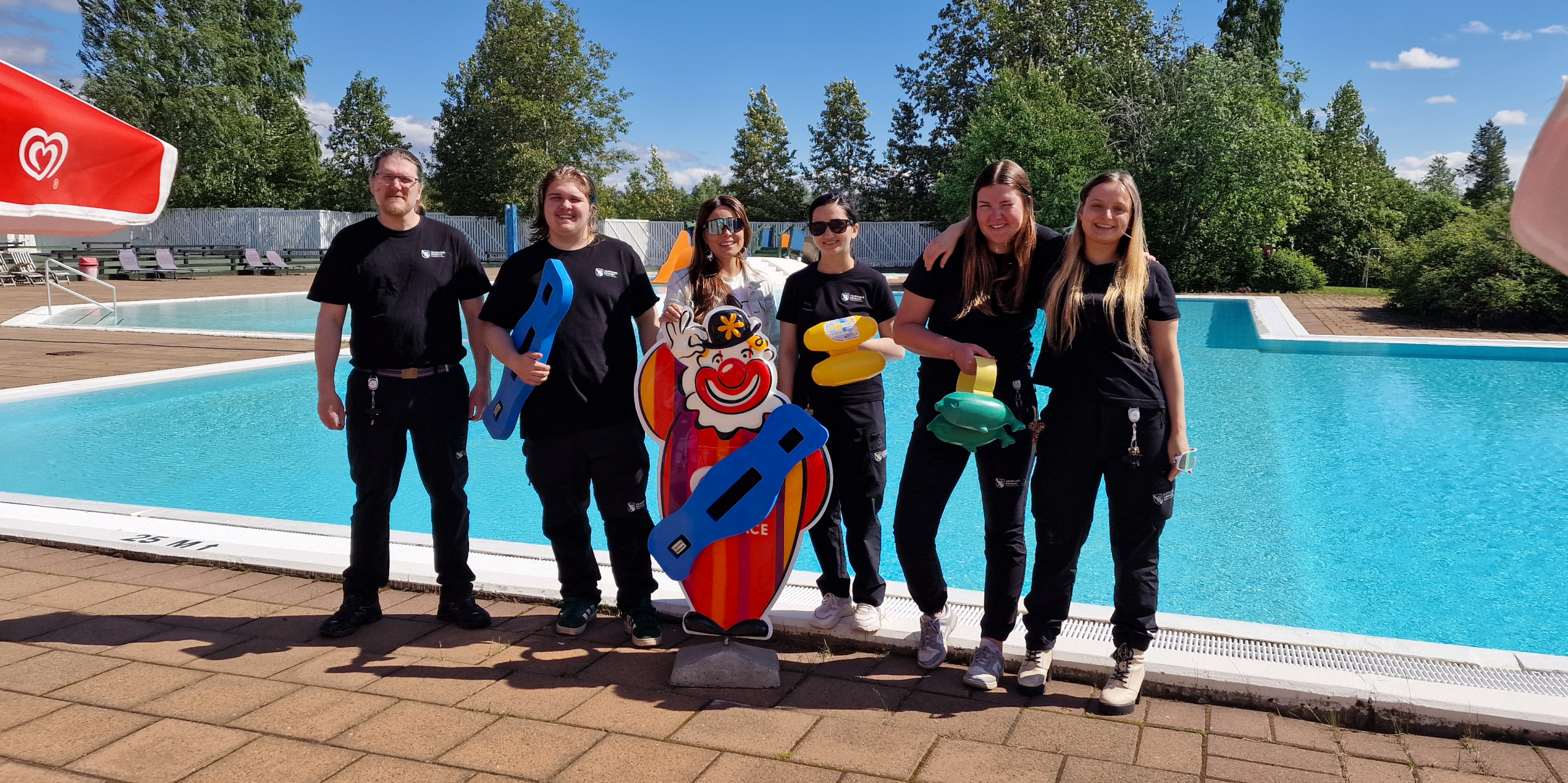 Badpersonalen framför Krajas pool en tidig sommardag.