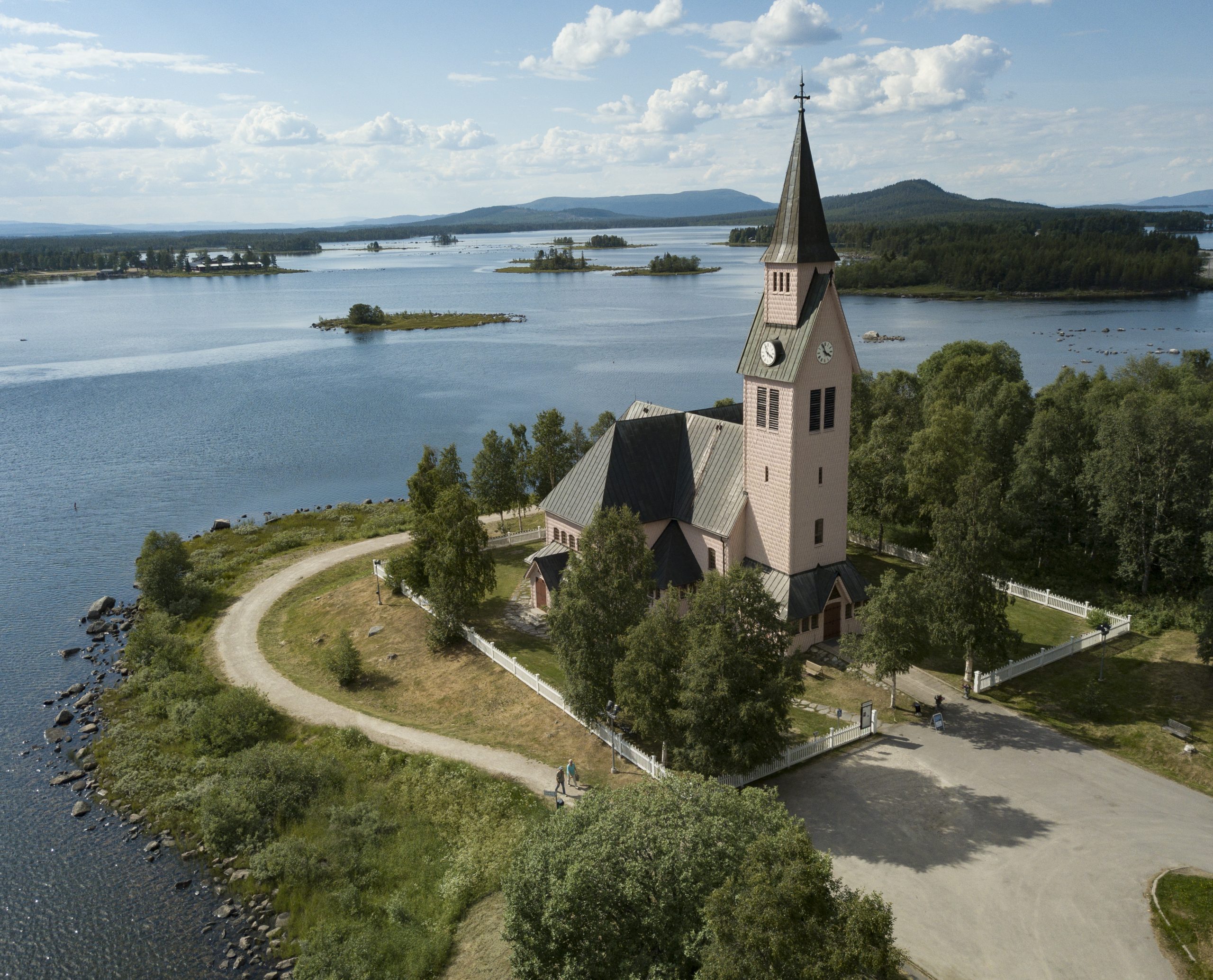 Kyrkan med vatten i bakgrunden en sommardag.
