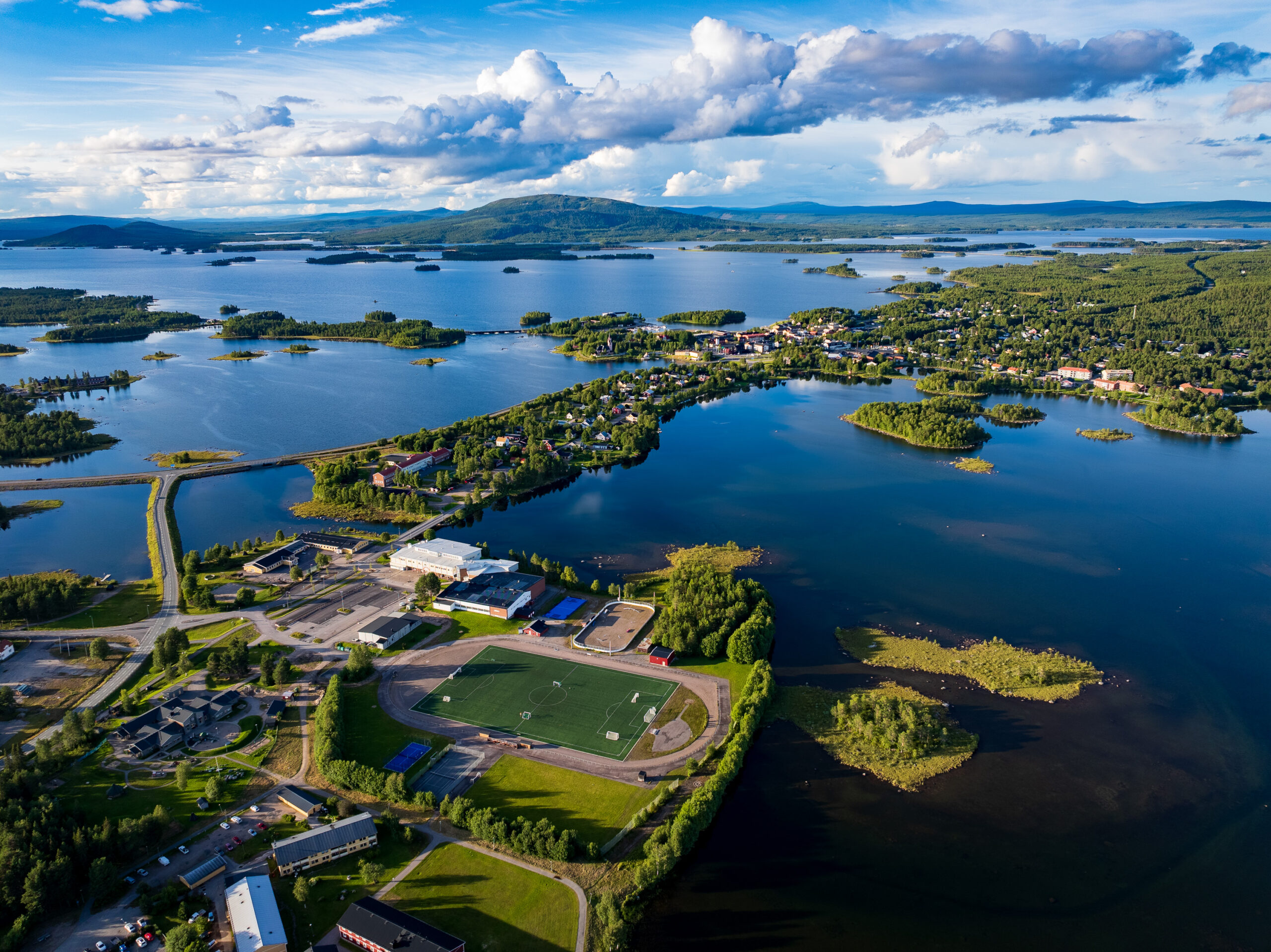 Flygfoto över campusområdet och Arjeplogs tätort en sommardag.